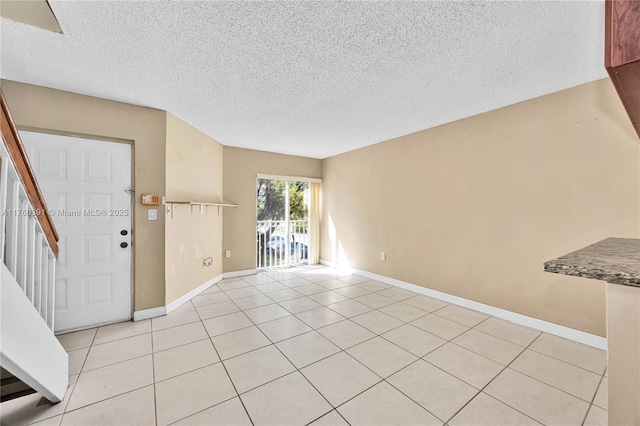 interior space featuring stairway, light tile patterned flooring, and baseboards