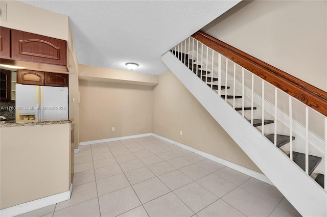 interior space with baseboards, a textured ceiling, and tile patterned flooring