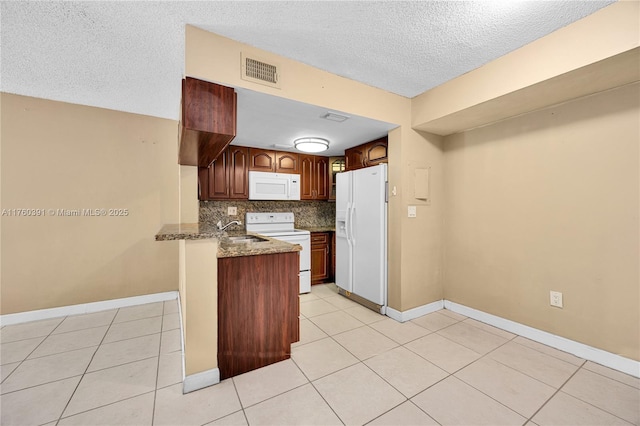 kitchen featuring white appliances, visible vents, a peninsula, a sink, and decorative backsplash