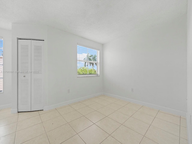 8585 NW 6th Ln Unit 9-208, Miami, FL 33126 - unfurnished bedroom with a textured ceiling, light tile patterned flooring, and a closet