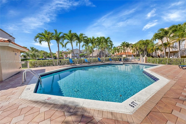 community pool with a patio area and fence