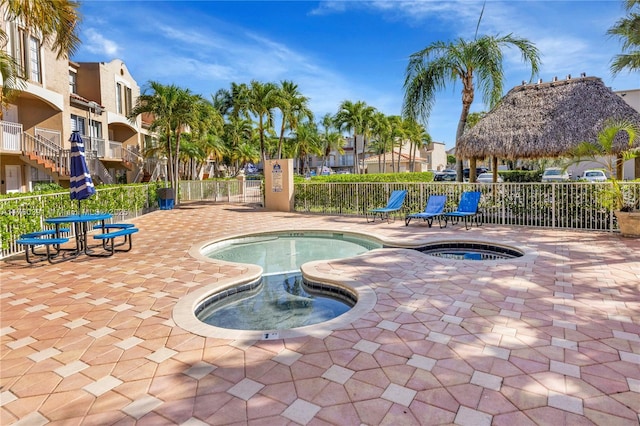 view of swimming pool with a community hot tub and fence