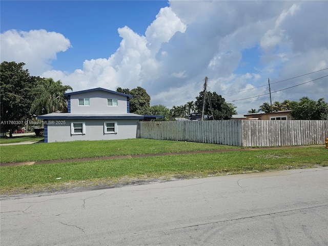 view of property exterior featuring stucco siding, a lawn, and fence