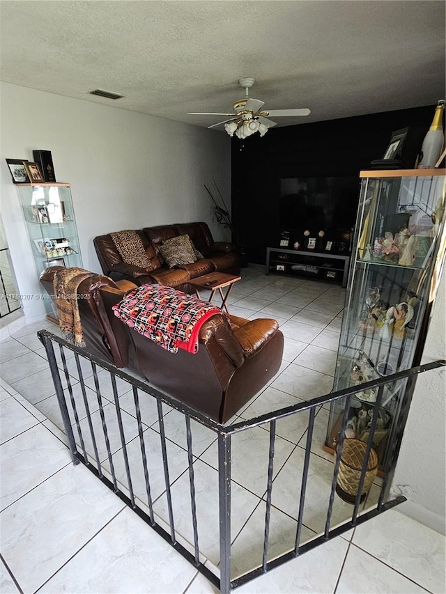 living area featuring ceiling fan, tile patterned floors, and a textured ceiling