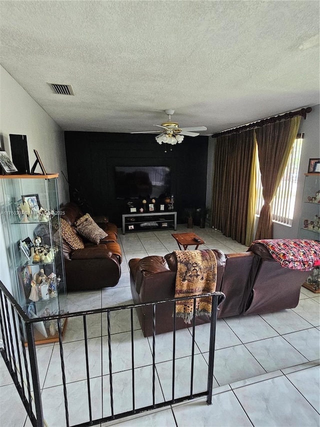 living room featuring visible vents, a textured ceiling, and ceiling fan