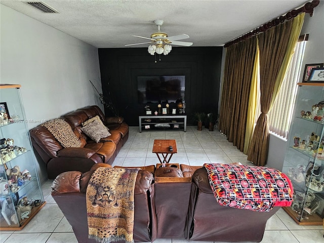 tiled living area featuring visible vents, a textured ceiling, and a ceiling fan