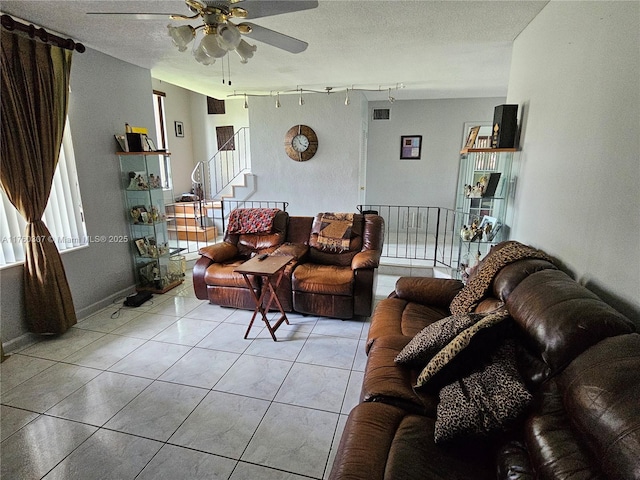 living area featuring ceiling fan, a textured ceiling, light tile patterned flooring, and track lighting