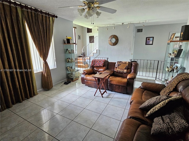 living room with visible vents, a textured ceiling, rail lighting, tile patterned flooring, and stairs