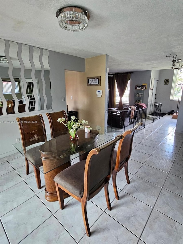 dining room with a textured ceiling, a healthy amount of sunlight, and light tile patterned flooring