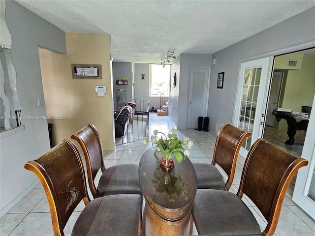 dining area featuring light tile patterned flooring, baseboards, and a textured ceiling