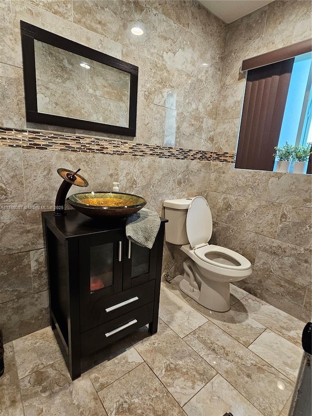 bathroom with vanity, tile walls, and toilet