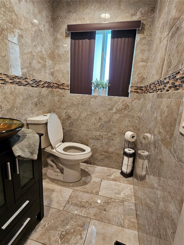 bathroom featuring a sink, toilet, and tile walls