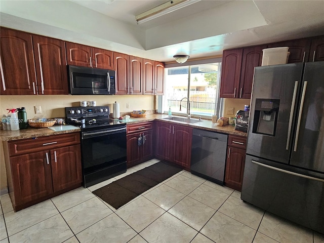 kitchen with dark countertops, light tile patterned floors, appliances with stainless steel finishes, and a sink