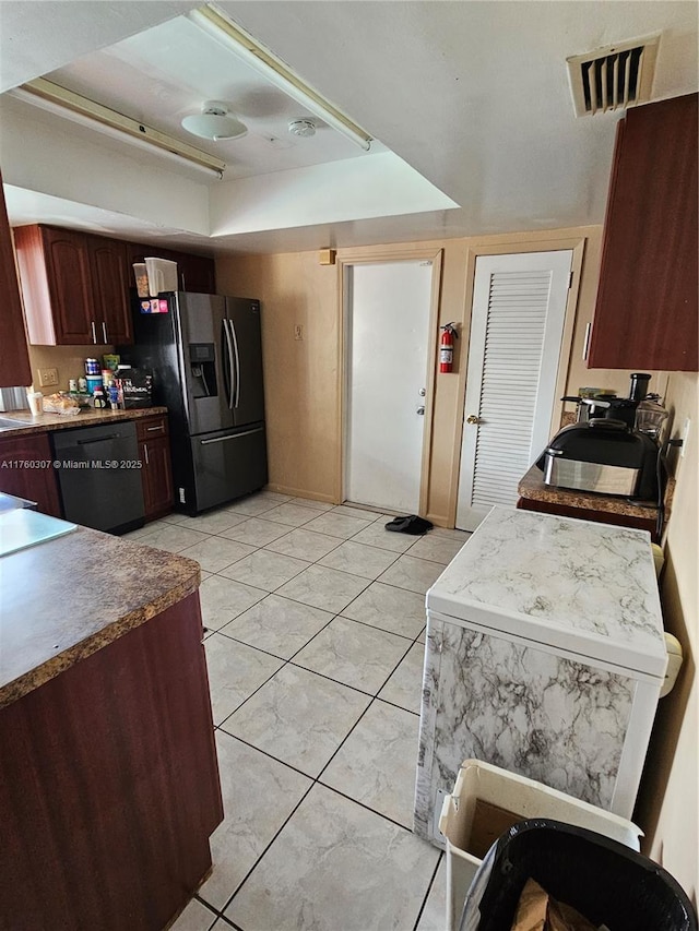 kitchen with visible vents, a tray ceiling, stainless steel fridge, light tile patterned floors, and dishwasher