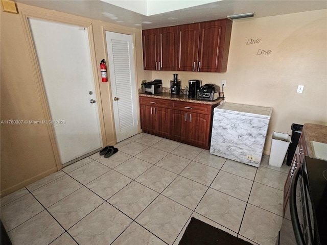 kitchen with light stone counters, light tile patterned floors, and range