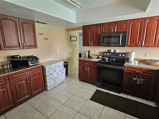 kitchen with light tile patterned floors, stainless steel microwave, and black electric range oven