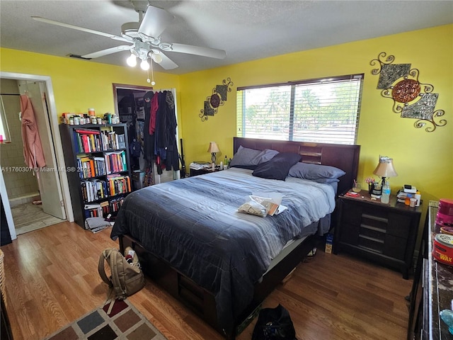 bedroom featuring a textured ceiling, ensuite bathroom, ceiling fan, and wood finished floors