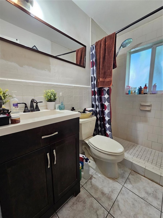 bathroom with toilet, tile walls, tile patterned flooring, tiled shower, and vanity