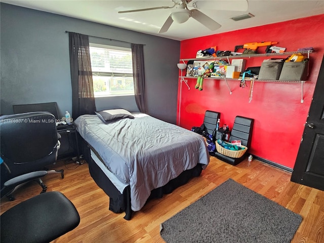 bedroom with wood finished floors, visible vents, and ceiling fan