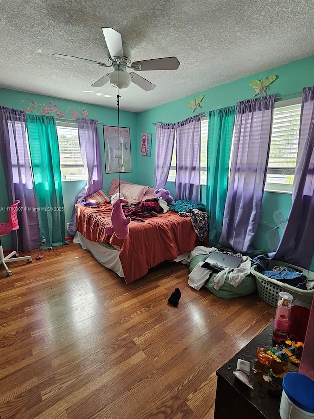 bedroom featuring ceiling fan, a textured ceiling, and wood finished floors