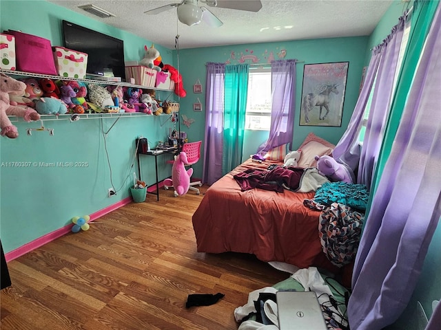 bedroom featuring visible vents, a textured ceiling, wood finished floors, and a ceiling fan