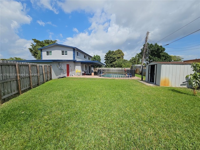 view of yard featuring an outbuilding, a shed, a fenced in pool, and a fenced backyard