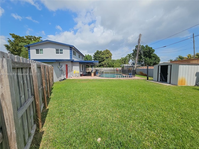 view of yard with an outbuilding, a fenced in pool, a storage unit, and a fenced backyard