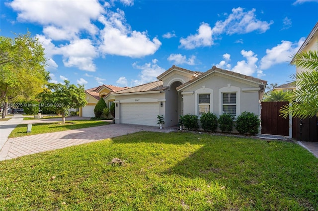 view of front of house featuring a tile roof, a front yard, stucco siding, decorative driveway, and a garage