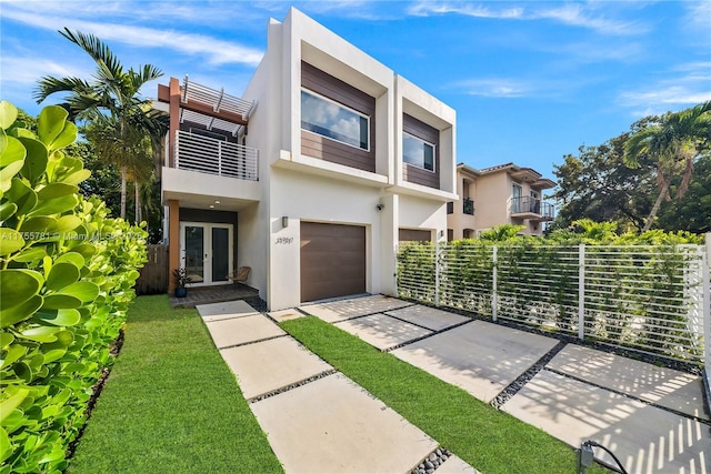 modern home with stucco siding, driveway, fence, french doors, and a balcony