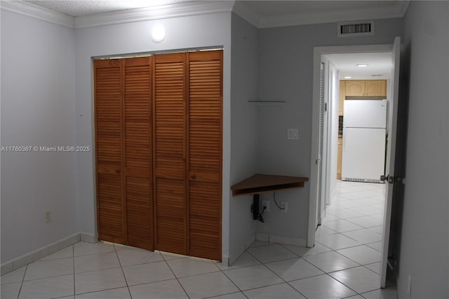 corridor featuring light tile patterned floors, visible vents, baseboards, and ornamental molding
