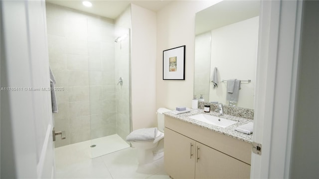 bathroom featuring tile patterned floors, tiled shower, toilet, and vanity