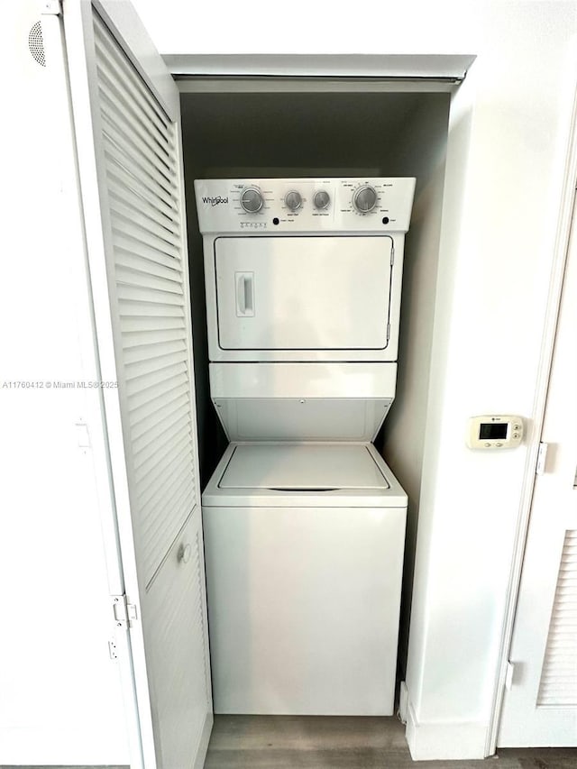 washroom with laundry area, stacked washer / drying machine, and wood finished floors