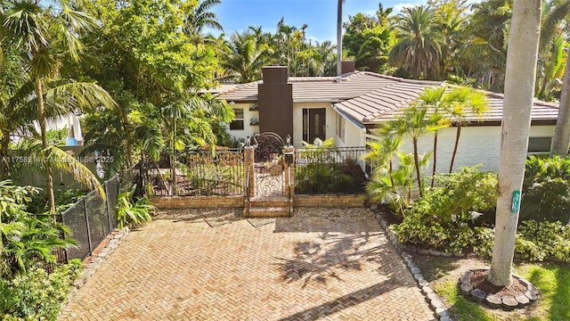 view of front facade with a gate, stucco siding, fence, and a tile roof