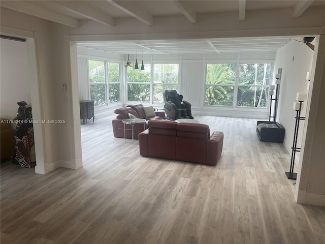 living room featuring beam ceiling, baseboards, and wood finished floors