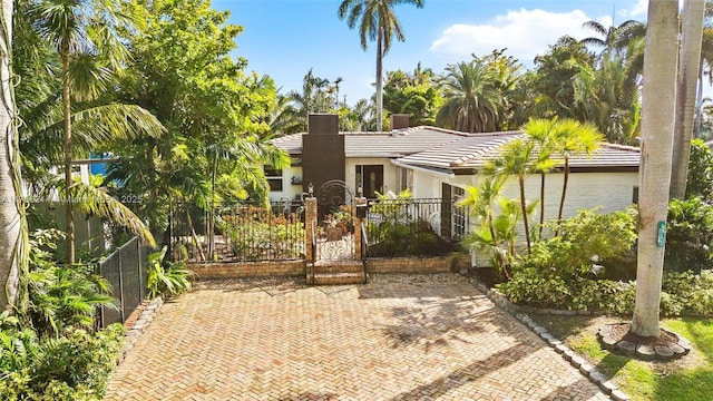 view of front of property featuring a gate, a fenced front yard, stucco siding, and a tiled roof