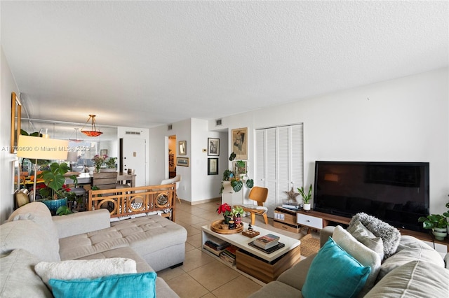 living area with tile patterned flooring, visible vents, and a textured ceiling