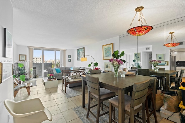 dining room featuring light tile patterned flooring, a view of city, a textured ceiling, and expansive windows