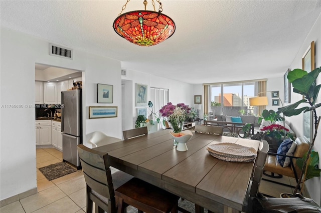 dining space with a view of city, light tile patterned floors, visible vents, and a textured ceiling