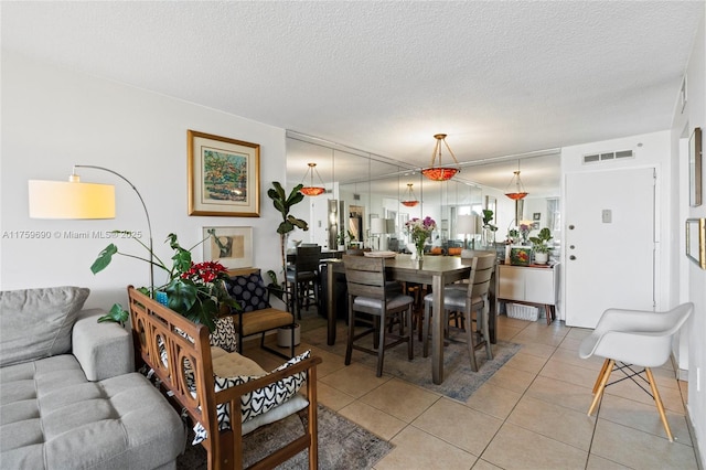 dining room featuring light tile patterned flooring, visible vents, and a textured ceiling