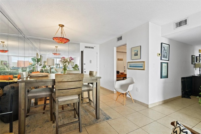 dining area with light tile patterned floors, visible vents, and a textured ceiling