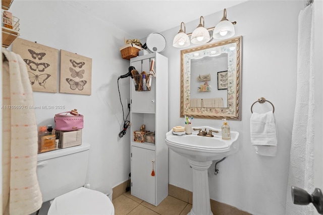 bathroom with tile patterned floors, toilet, and baseboards