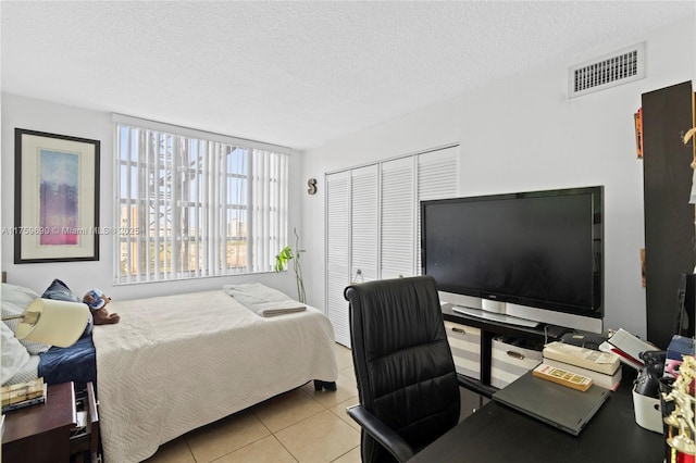 tiled bedroom featuring visible vents, a closet, and a textured ceiling