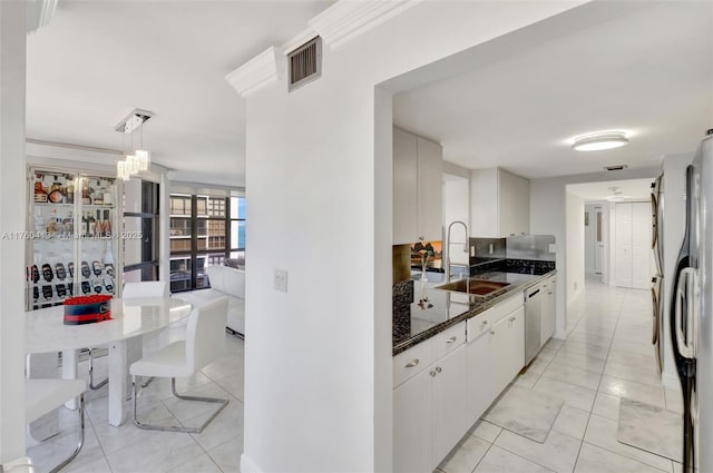 kitchen featuring visible vents, a sink, freestanding refrigerator, white cabinets, and dishwashing machine