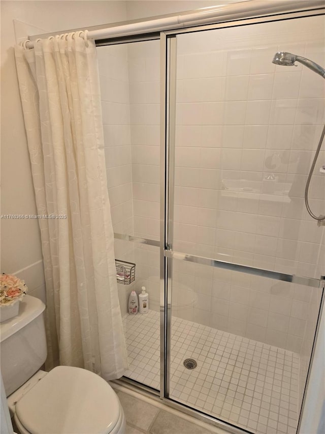 bathroom with tile patterned floors, toilet, and a stall shower