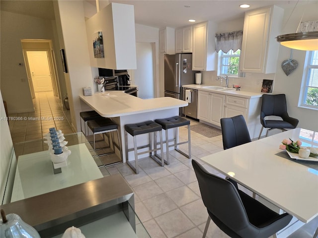 kitchen featuring a sink, appliances with stainless steel finishes, a breakfast bar, and white cabinets