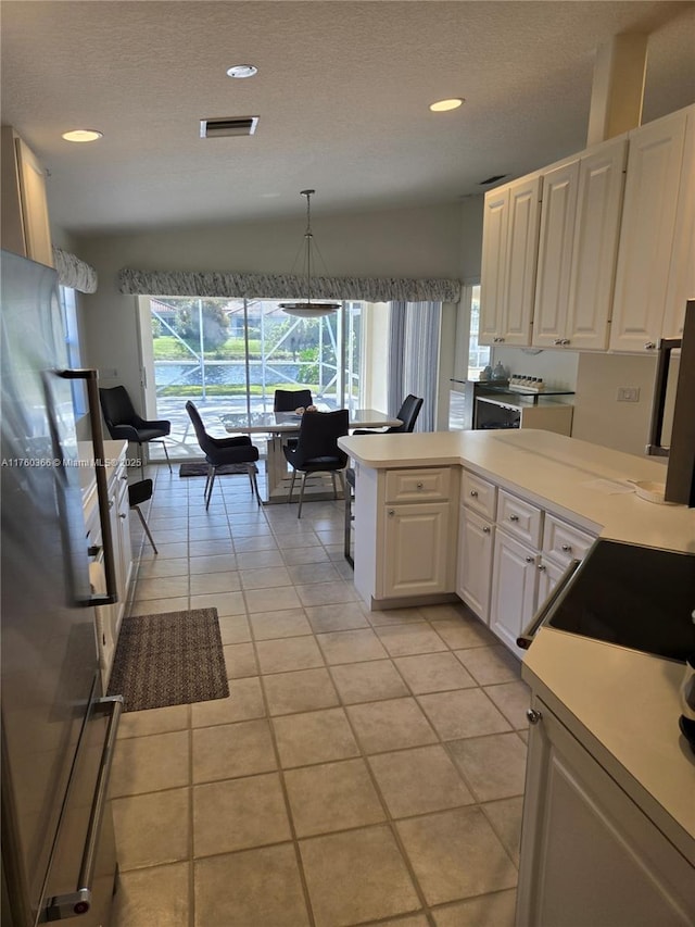 kitchen featuring visible vents, white cabinetry, light countertops, freestanding refrigerator, and a textured ceiling