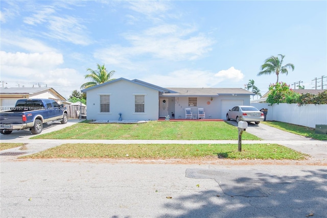 ranch-style home featuring aphalt driveway, a garage, a front yard, and fence