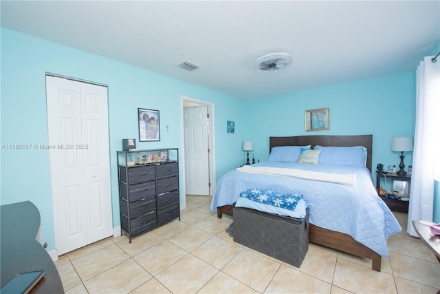 bedroom with light tile patterned floors, visible vents, and a closet