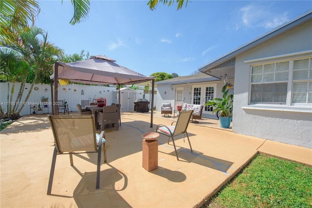 view of patio / terrace featuring a storage unit, an outbuilding, a fenced backyard, french doors, and outdoor dining area