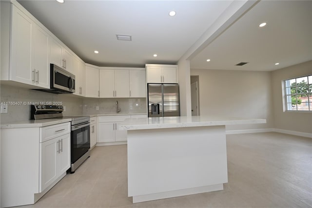 kitchen with tasteful backsplash, a center island, appliances with stainless steel finishes, white cabinetry, and a sink